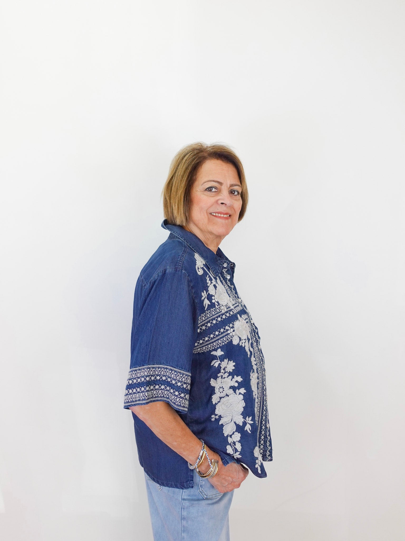 Woman wearing a blue embroidered shirt against a white background