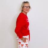Person wearing a red sweater and white shorts with red patterns against a plain background