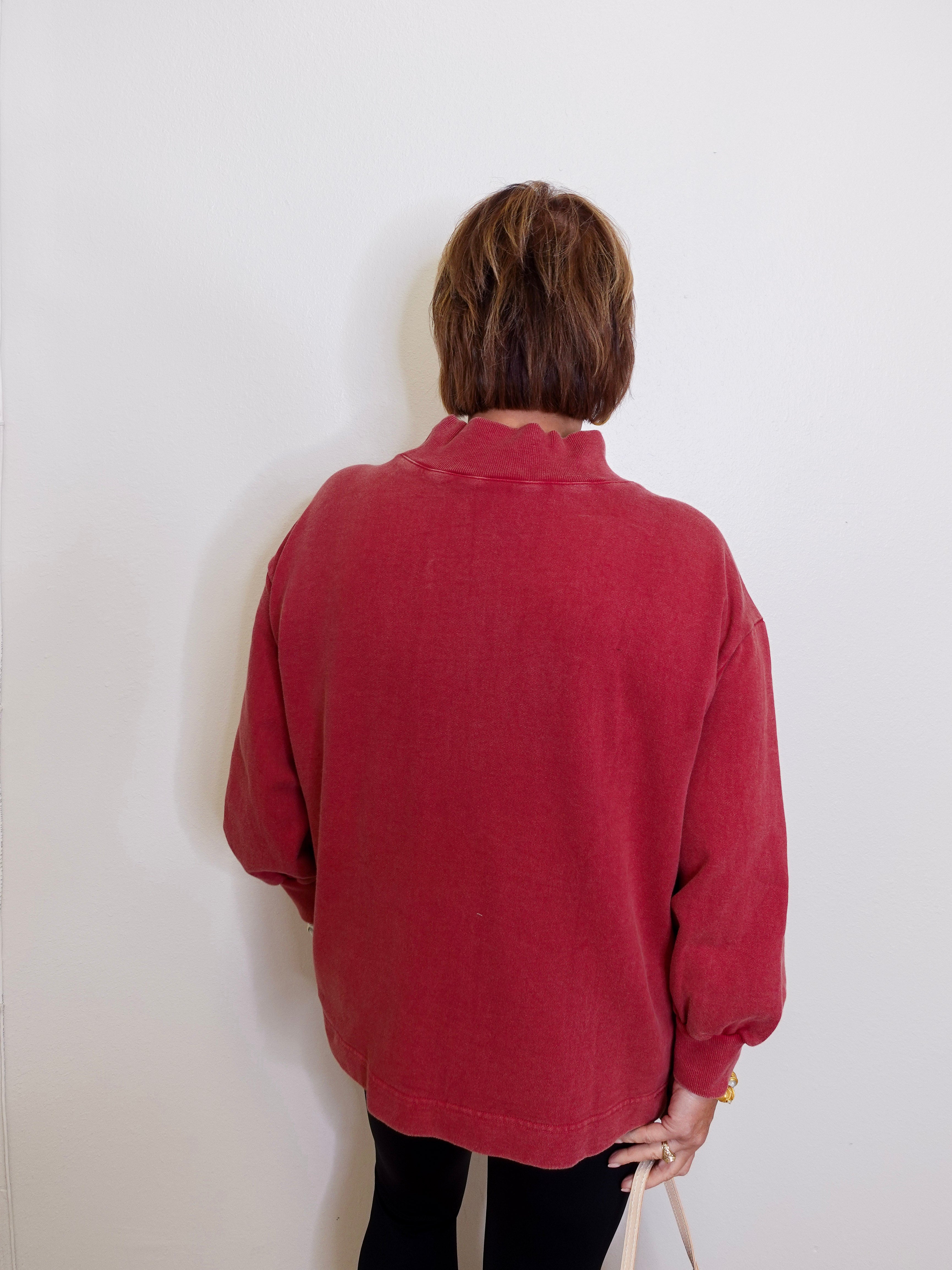 Person wearing a red sweater against a white wall