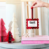 Decorative book with a 'tart' label, surrounded by pink and white paper trees on a table.