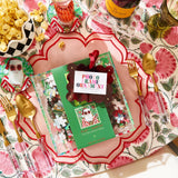Decorative table setting with a Prosecco bottle, popcorn, and a Christmas-themed ornament on a floral tablecloth.
