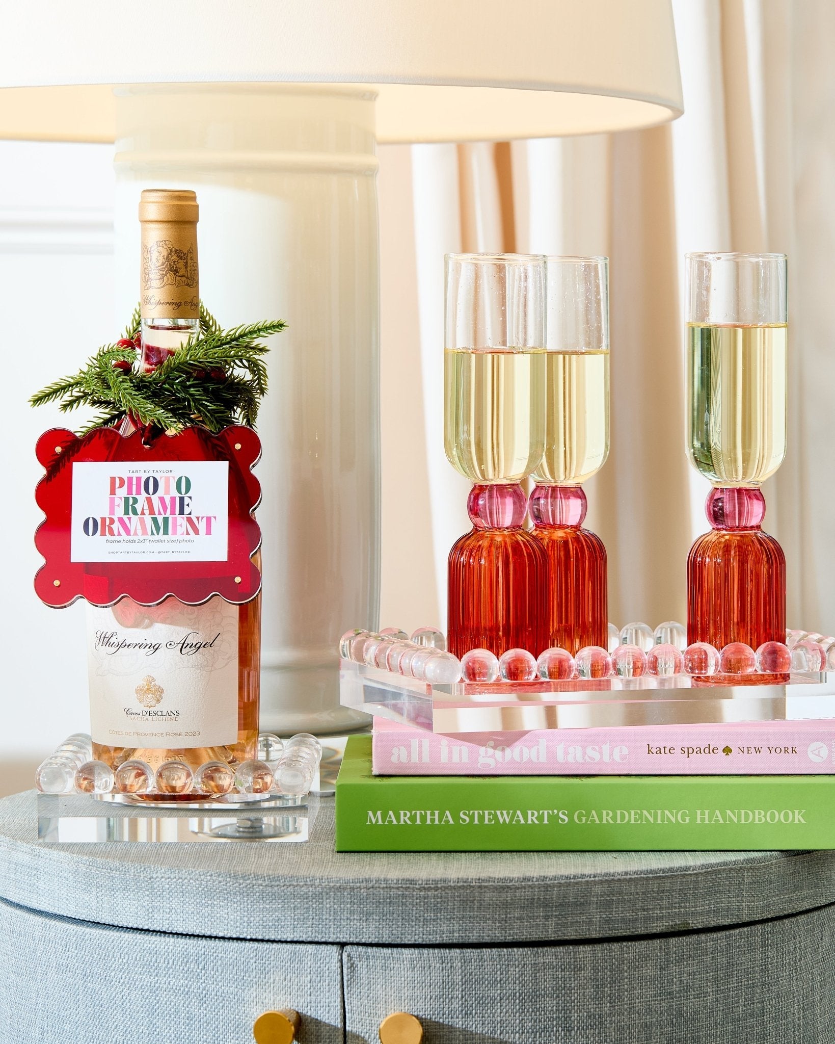 Wine bottle with decorative tag, glasses of champagne, and books on a table.