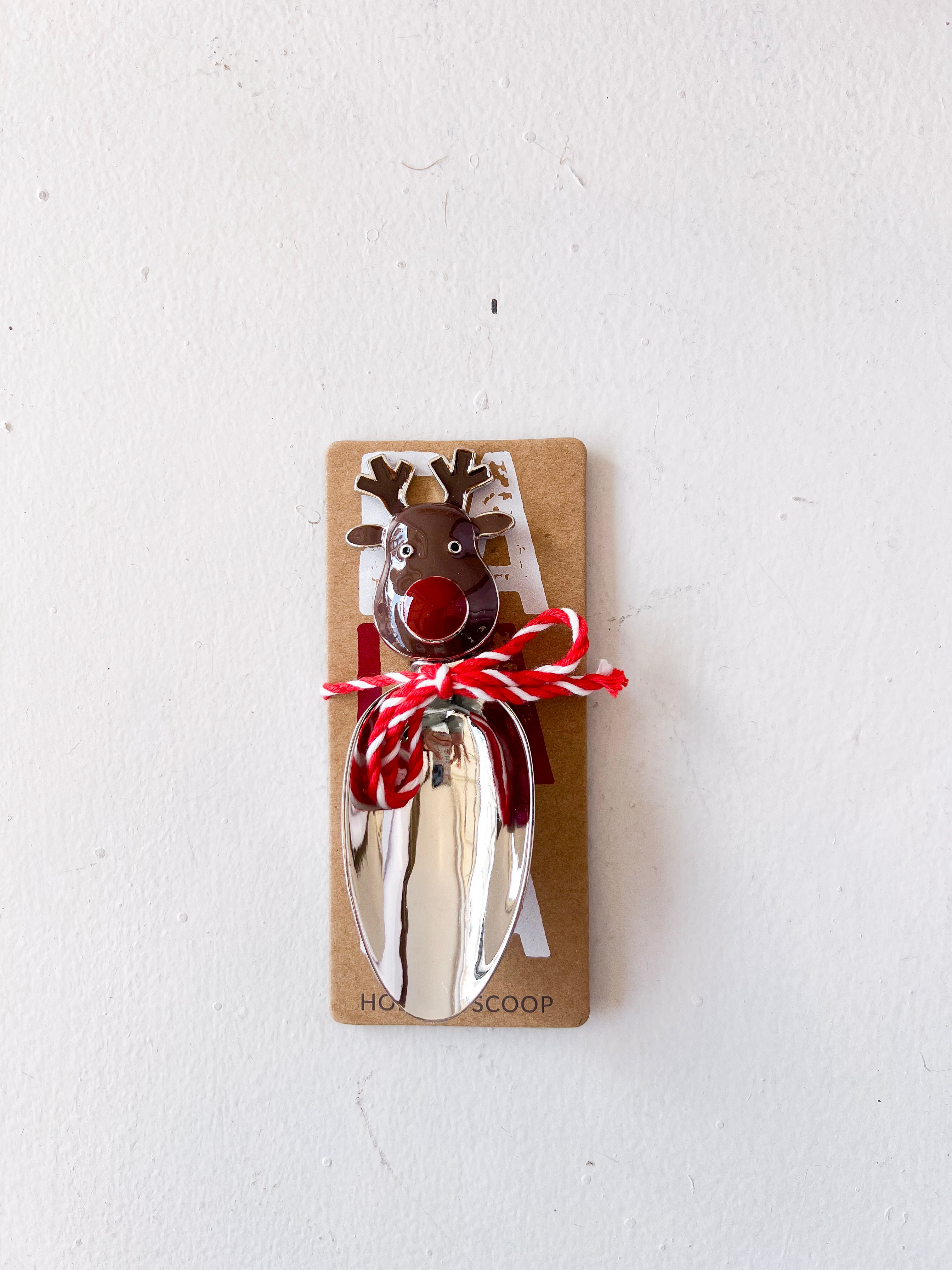 Metal bottle opener shaped like a reindeer on a cardboard backing with red string, against a white background.