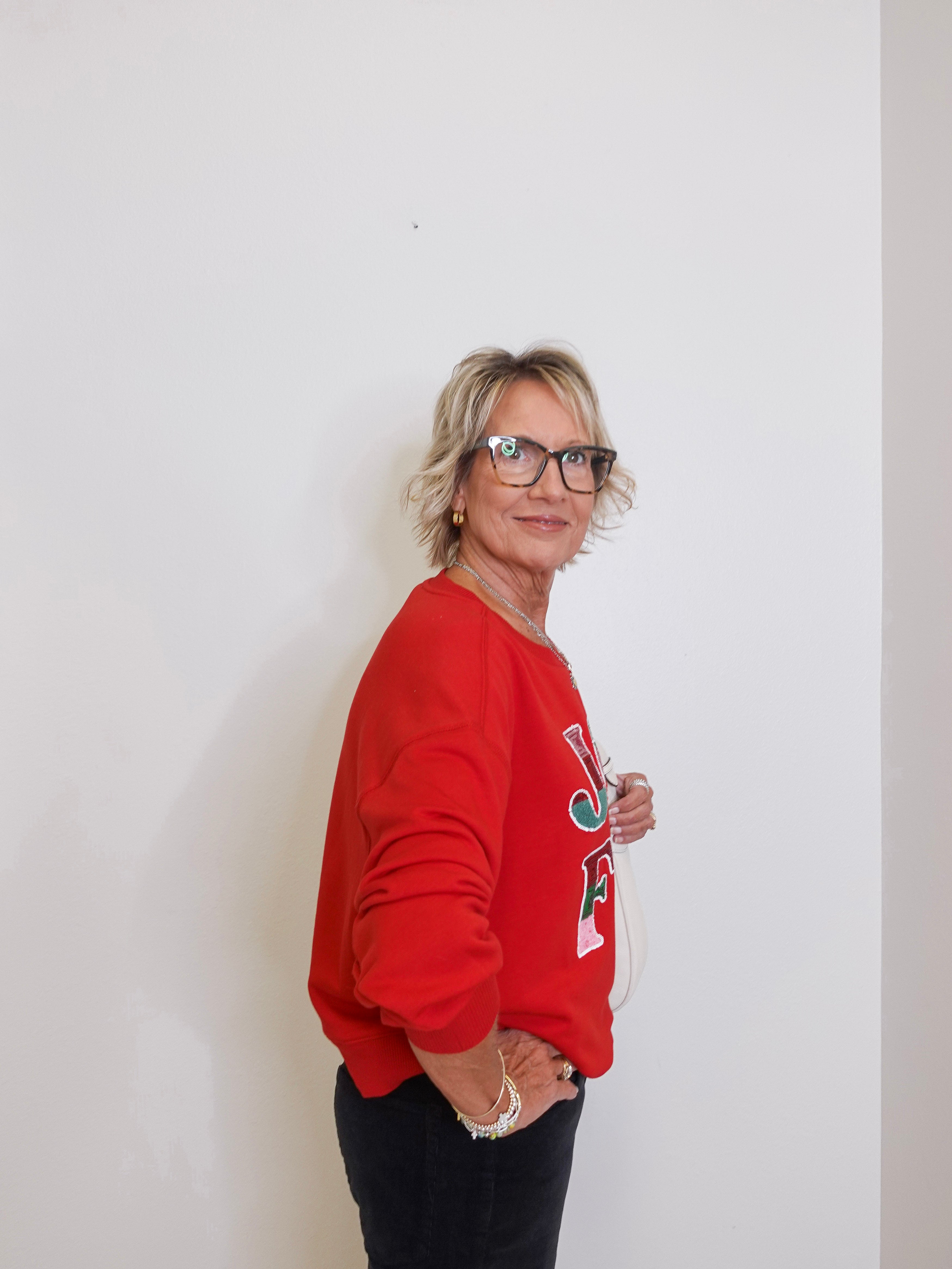 Person wearing a red sweatshirt with a logo against a white background
