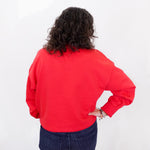 Person wearing a red sweatshirt and blue jeans against a white background