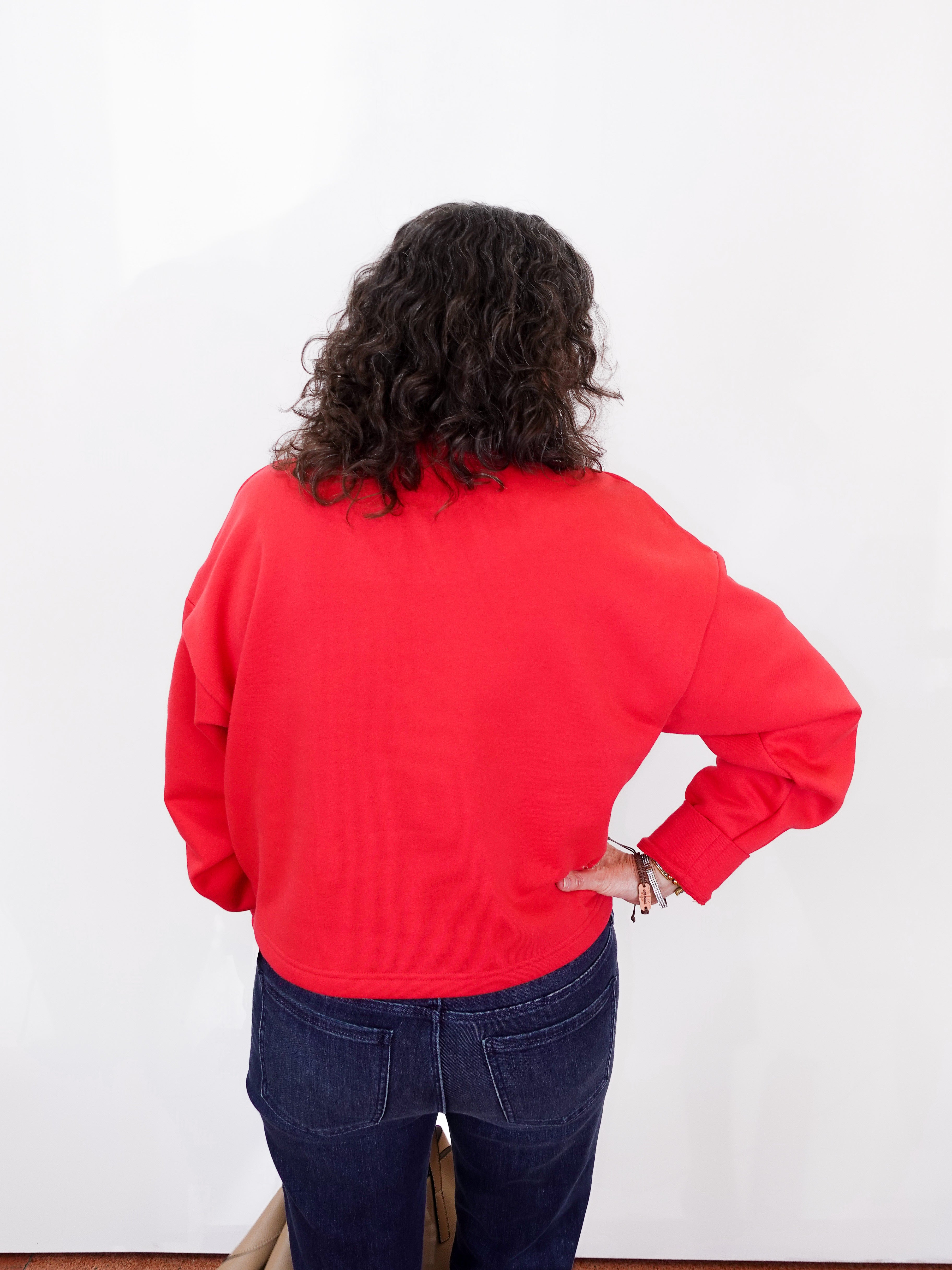 Person wearing a red sweatshirt and blue jeans against a white background