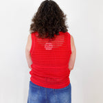 Person wearing a red crochet vest on a white background