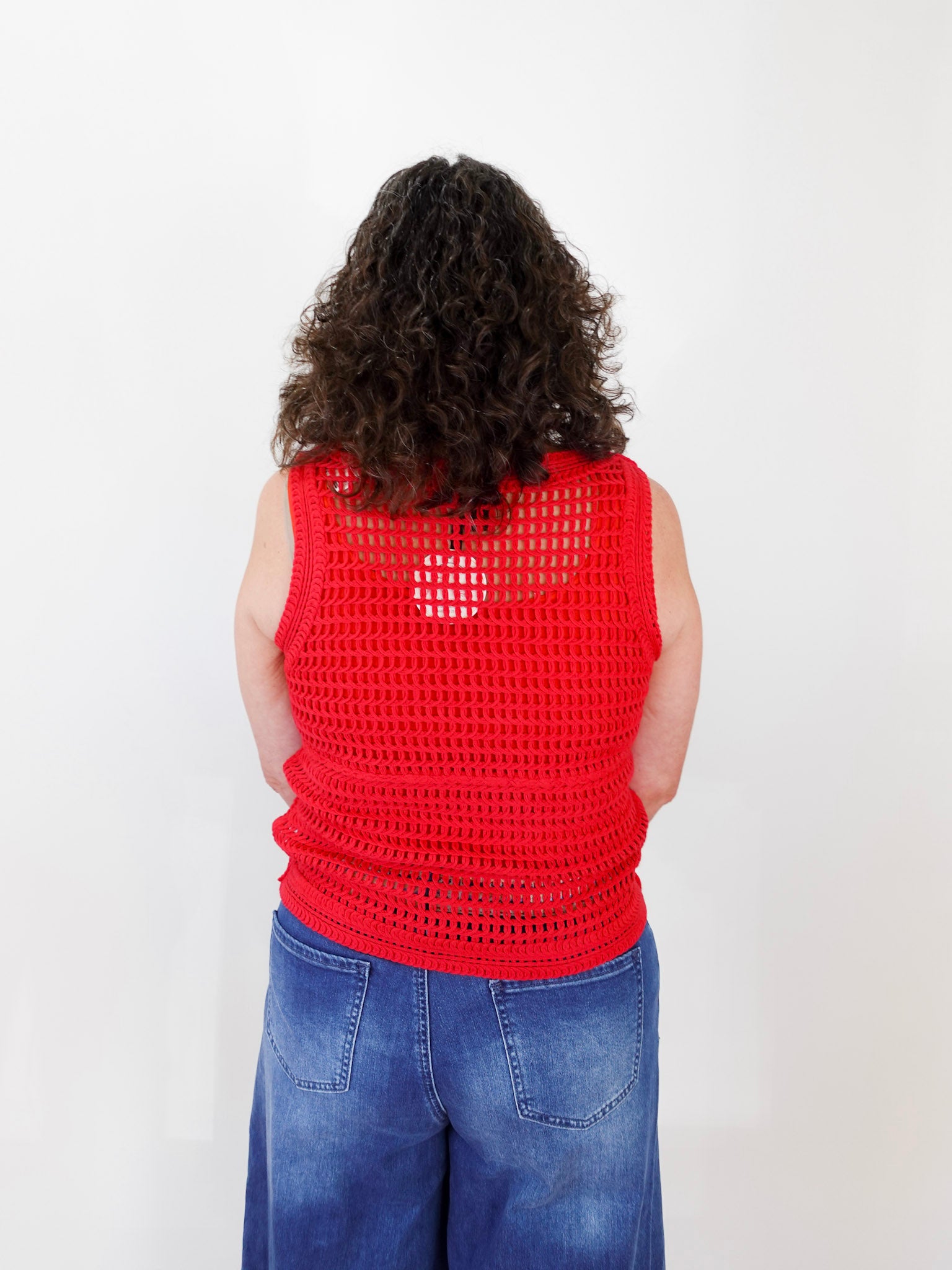 Person wearing a red crochet vest on a white background