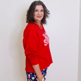 Woman wearing a red sweatshirt and colorful shorts against a white background