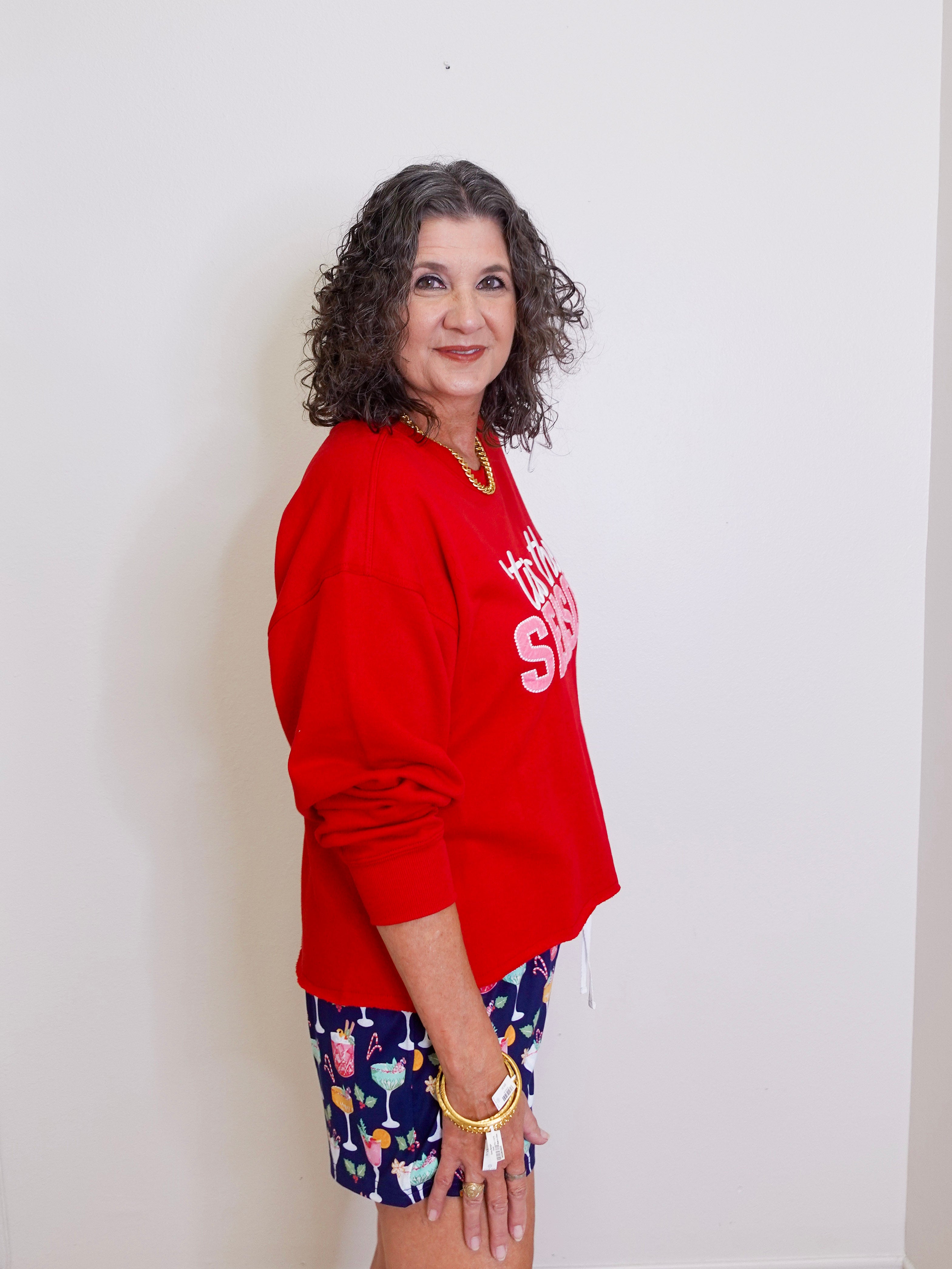 Woman wearing a red sweatshirt and colorful shorts against a white background