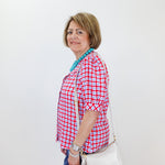 Woman wearing a red and white checkered shirt with a white bag against a white wall.