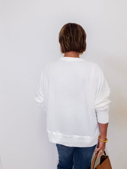 Person wearing a white sweatshirt and blue jeans against a plain background