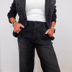 Person wearing a black jacket, white top, and black pants against a white background