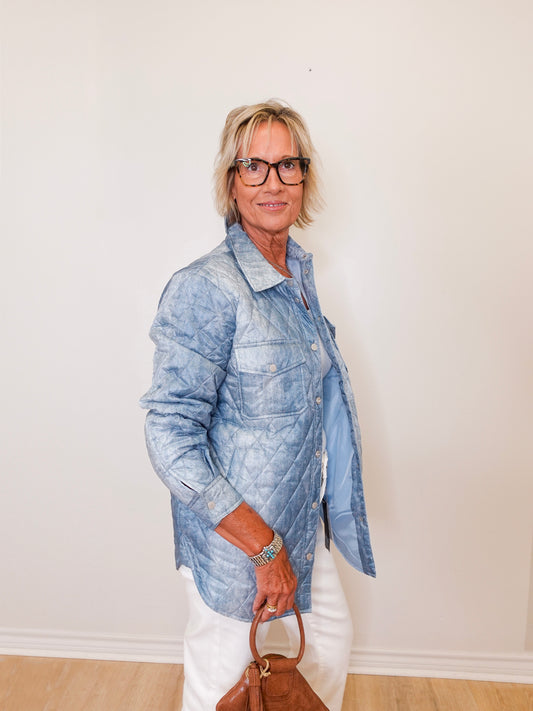 Person wearing a denim jacket and white pants against a plain background