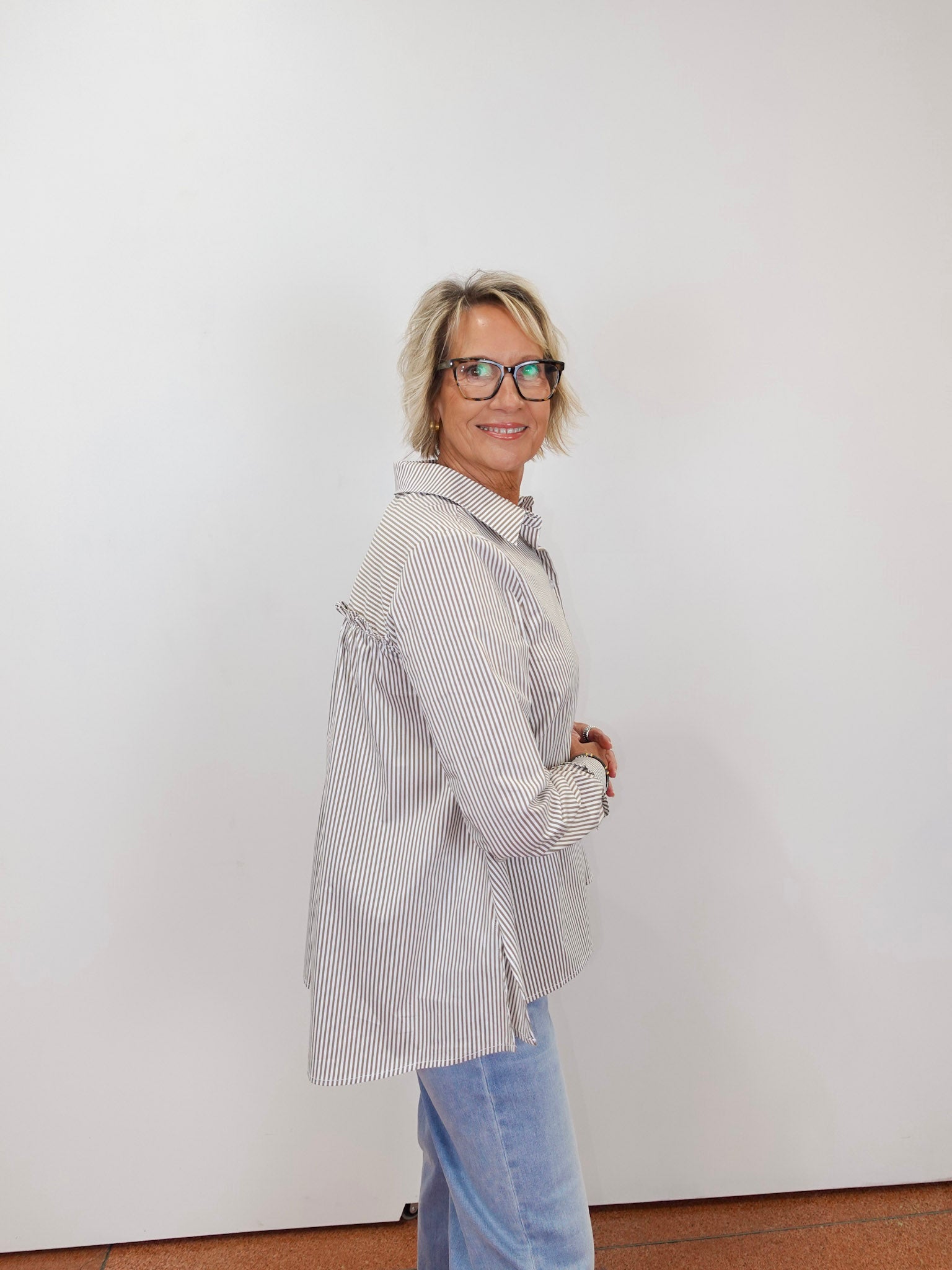 Woman wearing the Renuar striped long sleeve blouse with a classic button-front design.