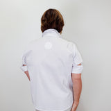 Person wearing a white shirt with cut-out sleeves against a plain background