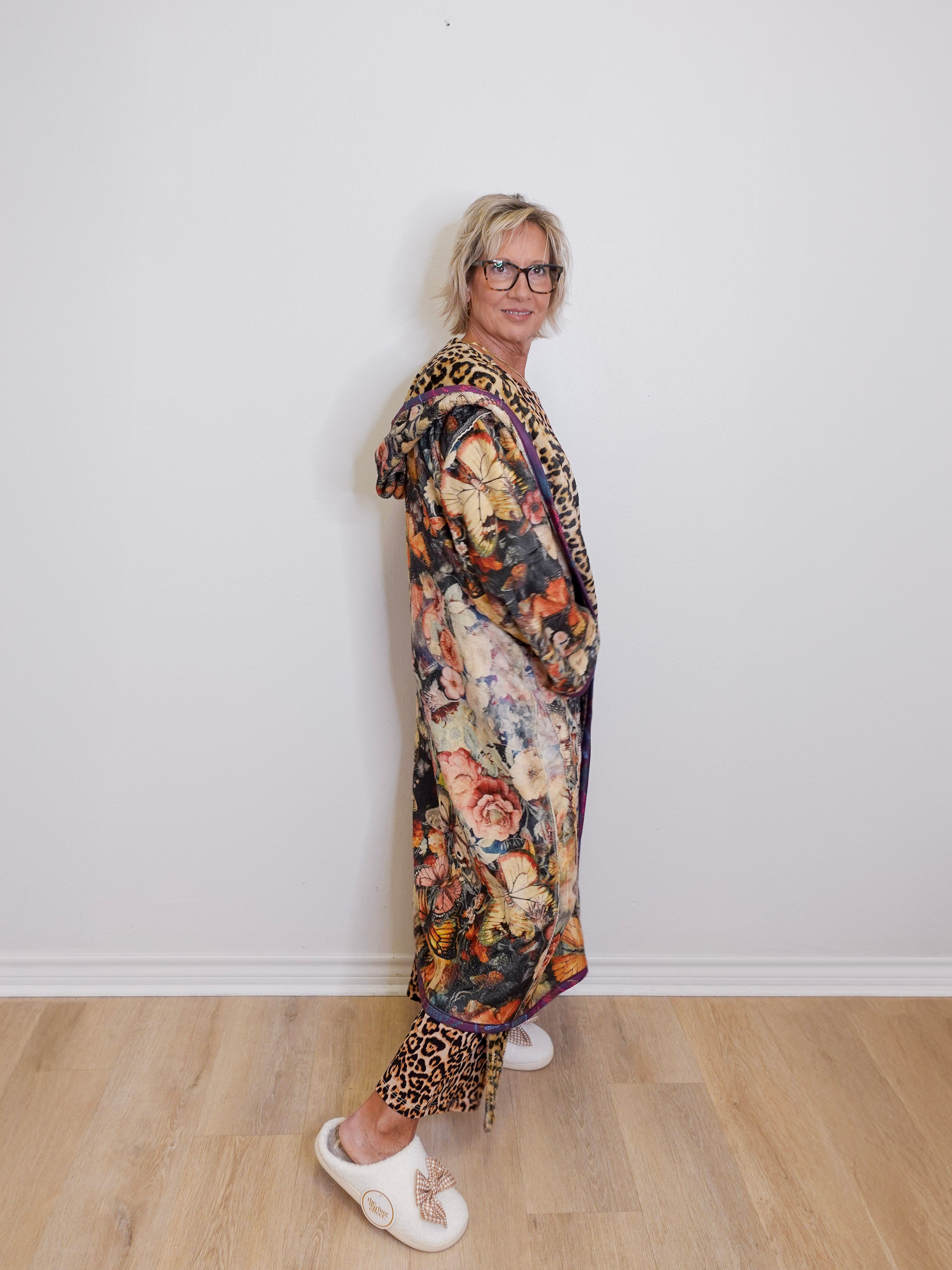 Person wearing a floral dress with leopard print accents against a white wall.