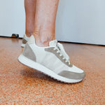 Person wearing gray and white sneakers on a speckled orange and brown floor.