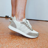 Person wearing gray and white sneakers on a speckled orange and brown floor.