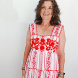 Woman wearing a red and white floral dress against a plain background