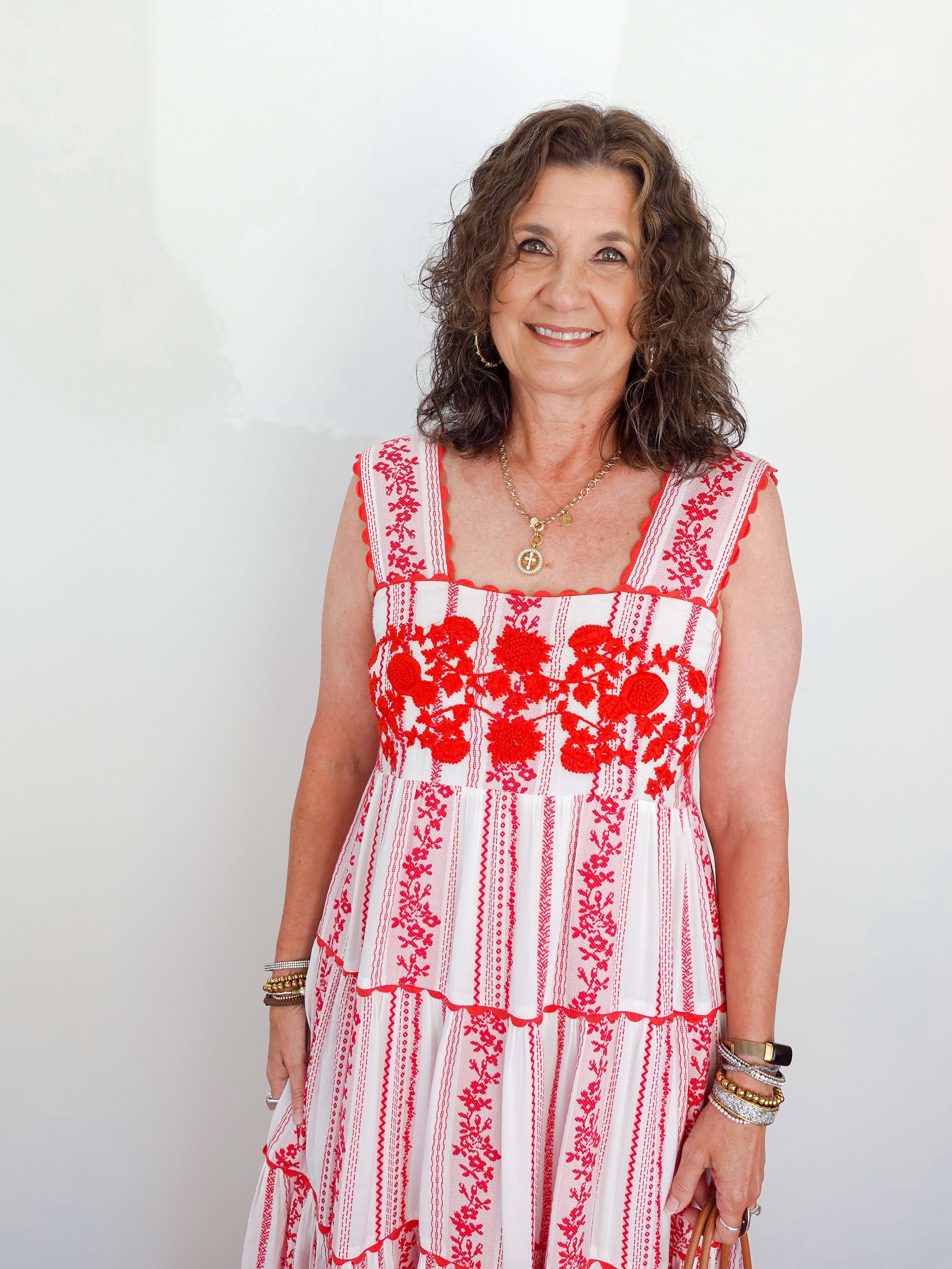 Woman wearing a red and white floral dress against a plain background