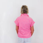 Person wearing a pink shirt and white pants against a white background