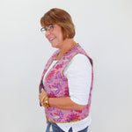 Woman wearing a colorful patterned vest over a white shirt on a white background