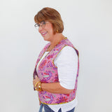 Woman wearing a colorful patterned vest over a white shirt on a white background