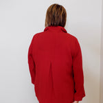 Person wearing a red jacket standing against a white wall