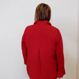 Person wearing a red jacket standing against a white wall