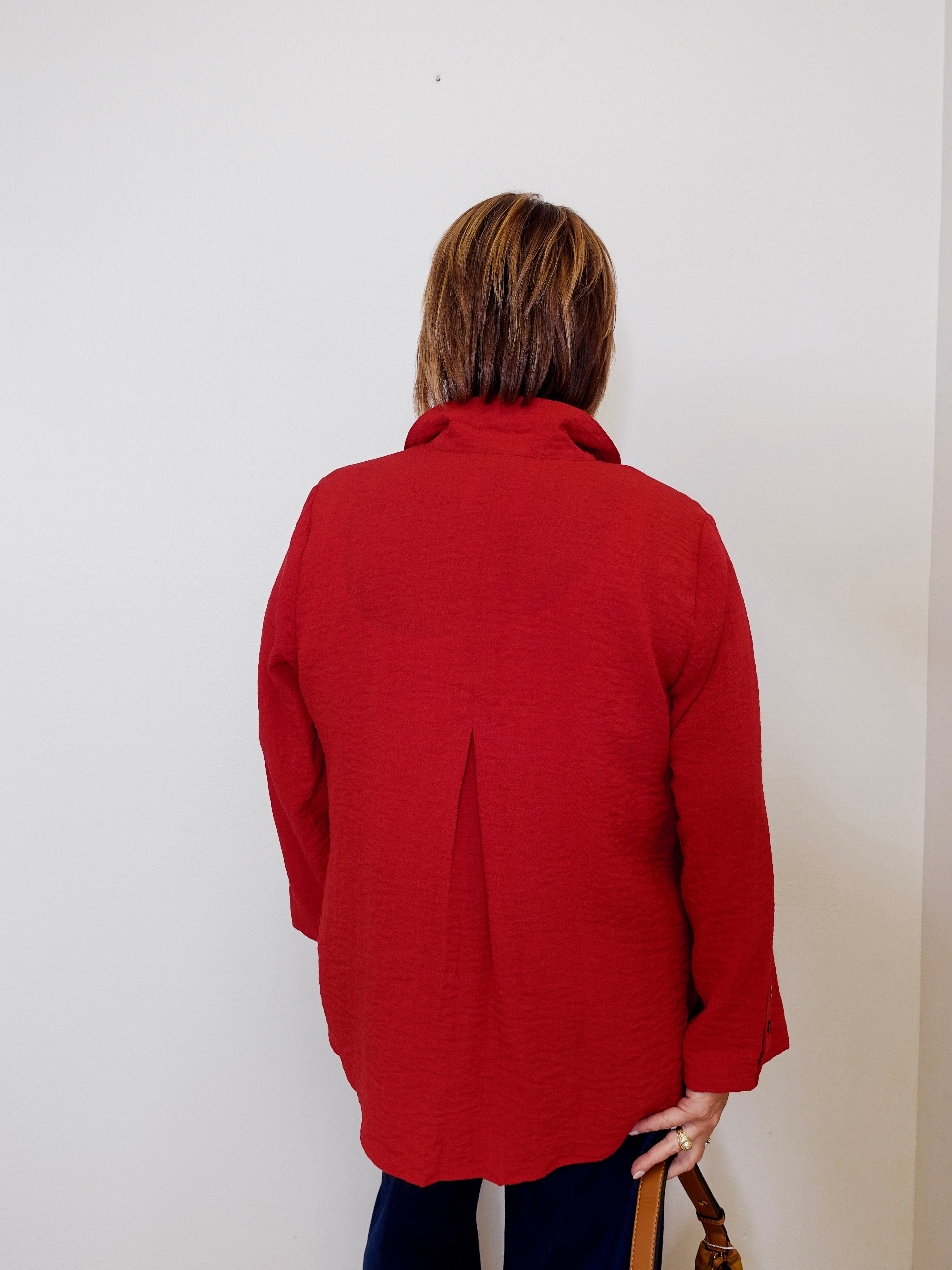Person wearing a red jacket standing against a white wall