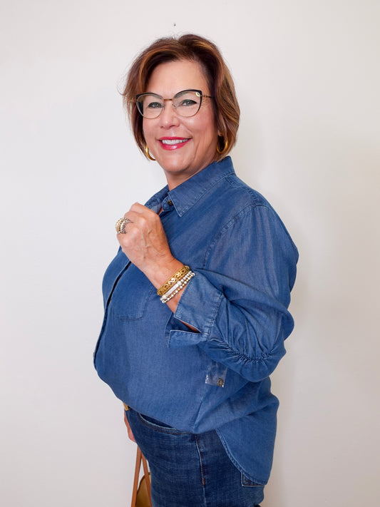 Woman wearing a blue Karen Kane denim shirt against a white background