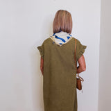 Woman wearing a green dress with a white wall background