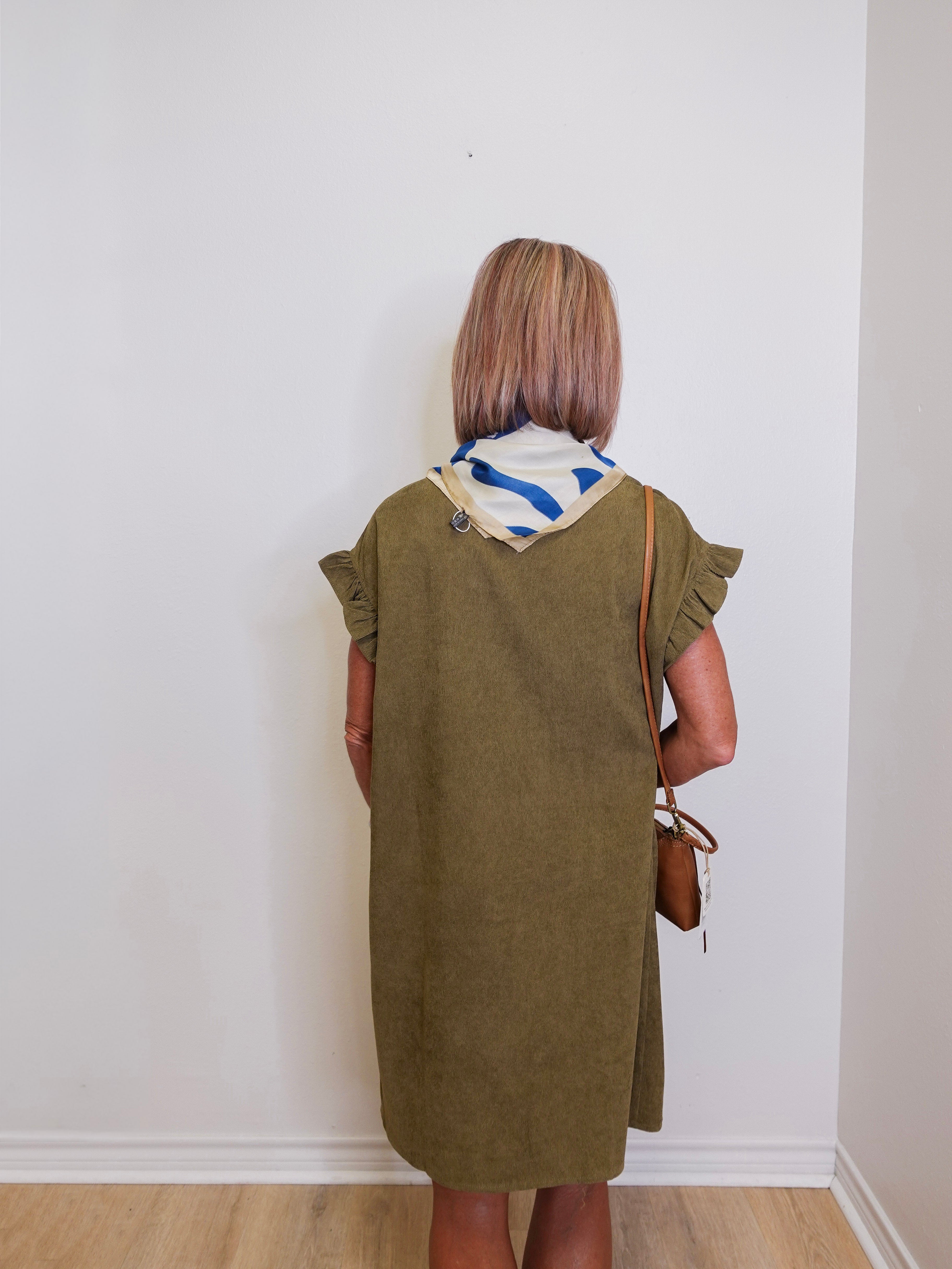 Woman wearing a green dress with a white wall background