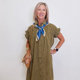 Woman wearing an olive green dress with a blue scarf against a white background
