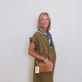 Woman wearing a green dress with a brown bag against a white wall
