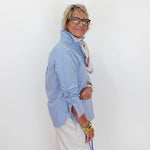 Person wearing a light blue shirt and white pants against a white background