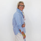 Person wearing a light blue shirt and white pants against a white background