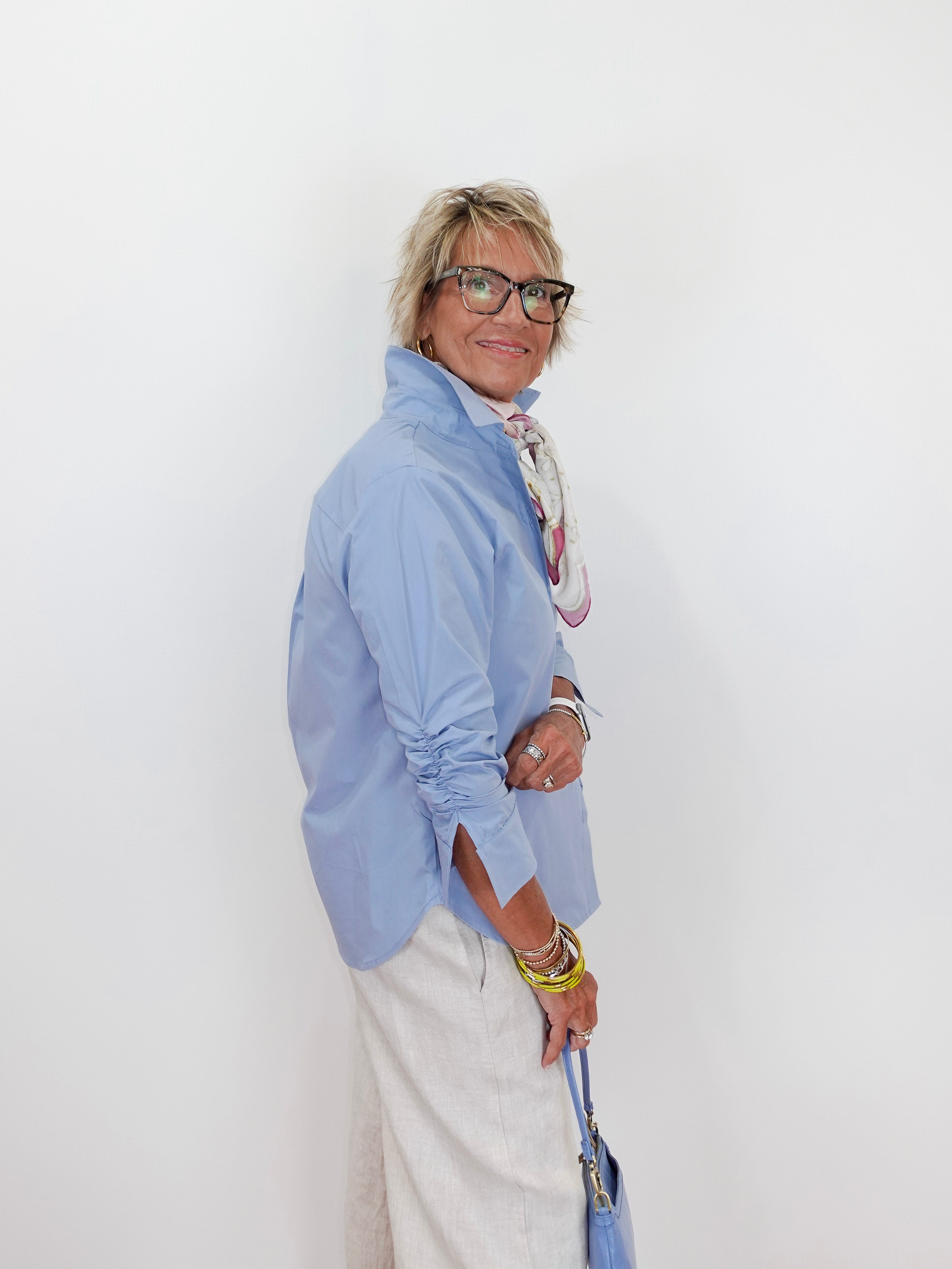 Person wearing a light blue shirt and white pants against a white background