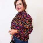 Woman wearing a colorful floral blouse against a white background
