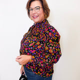 Woman wearing a colorful floral blouse against a white background