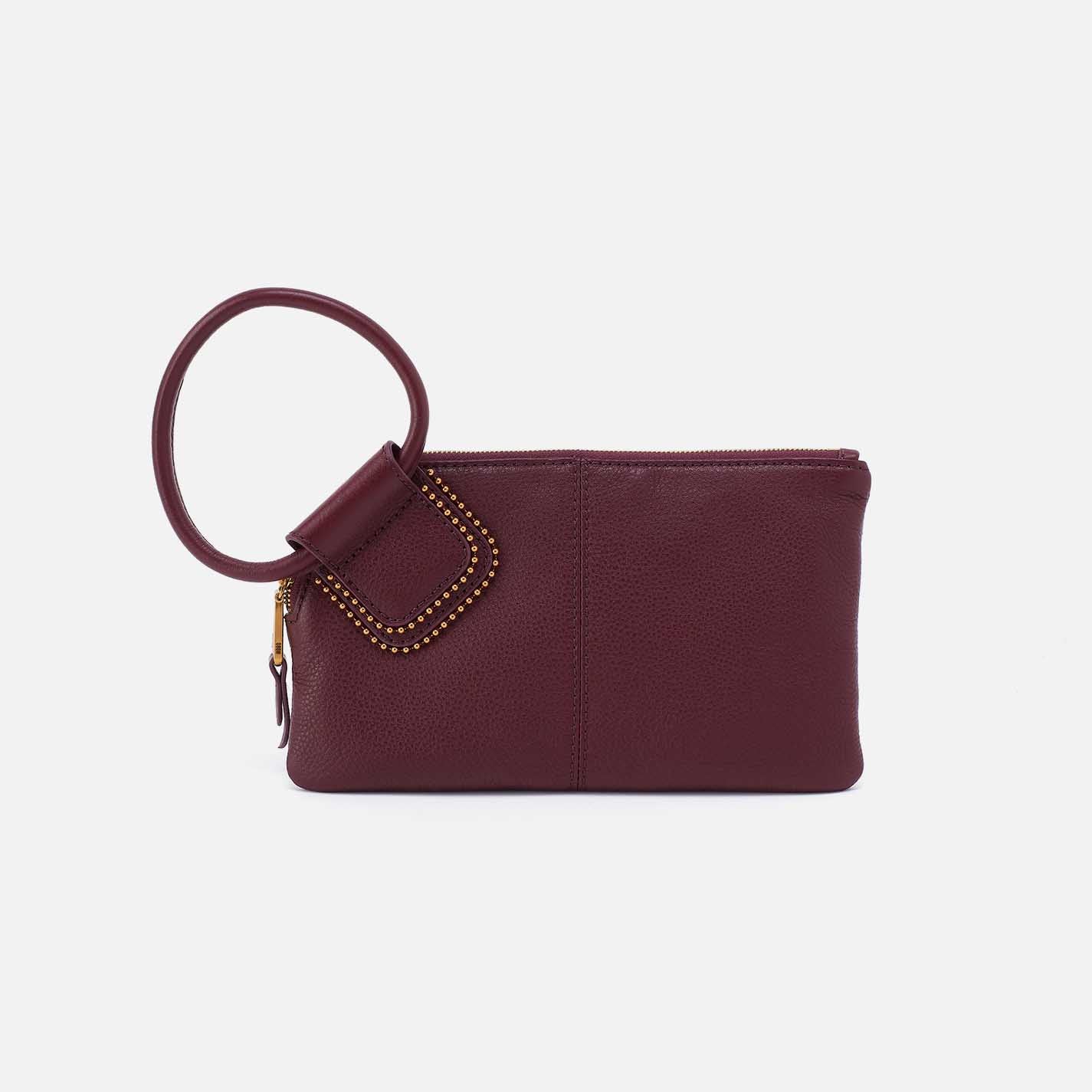 Maroon clutch bag with a ring handle on a light beige background