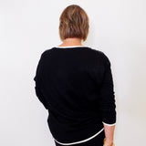 Person wearing a black outfit with white trim against a white background