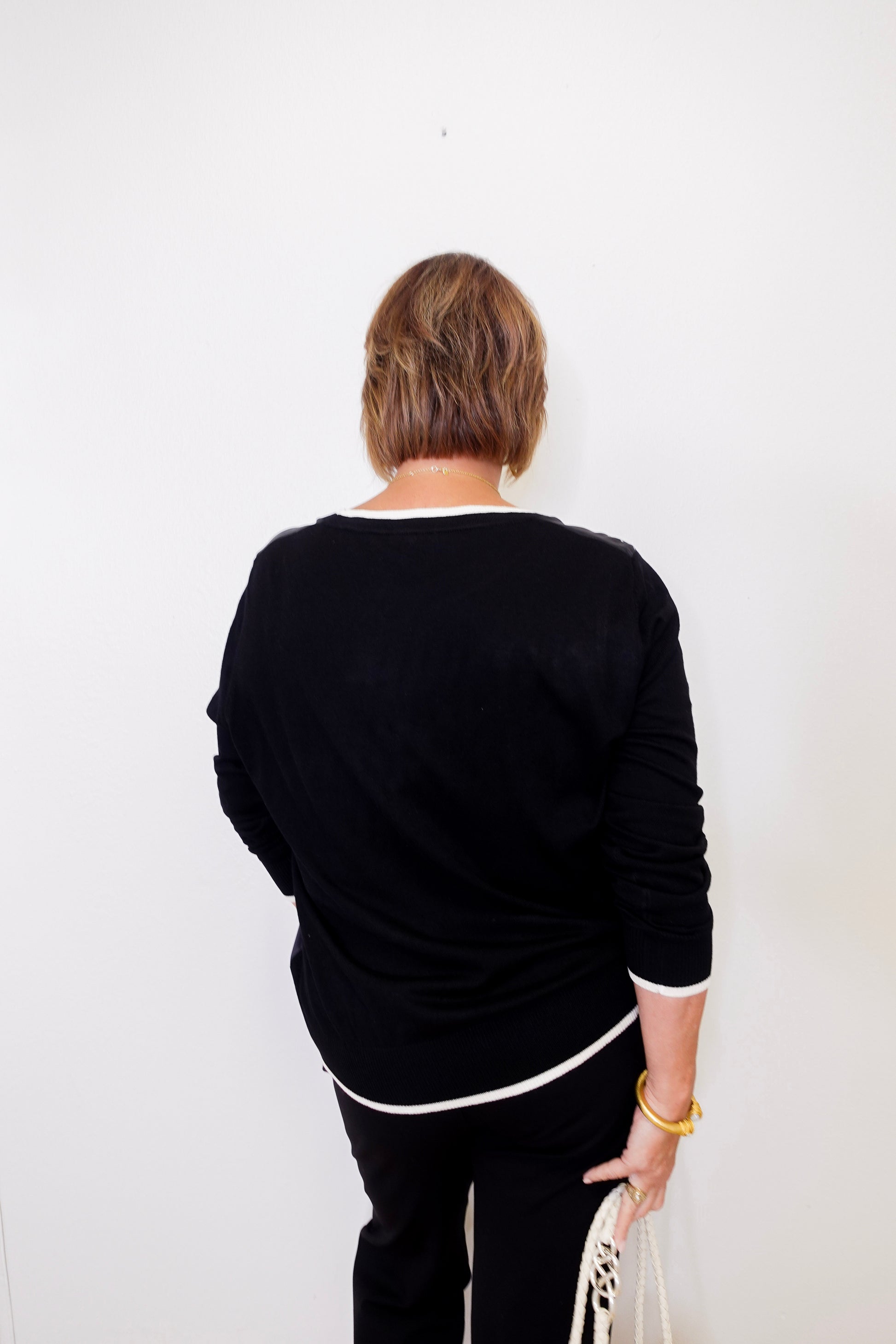 Person wearing a black outfit with white trim against a white background