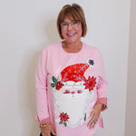 woman wearing a pink Santa baby long sleeve sweatshirt against a white background. 
