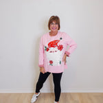 woman wearing a pink long sleeve Santa baby sweatshirt against a white background. 