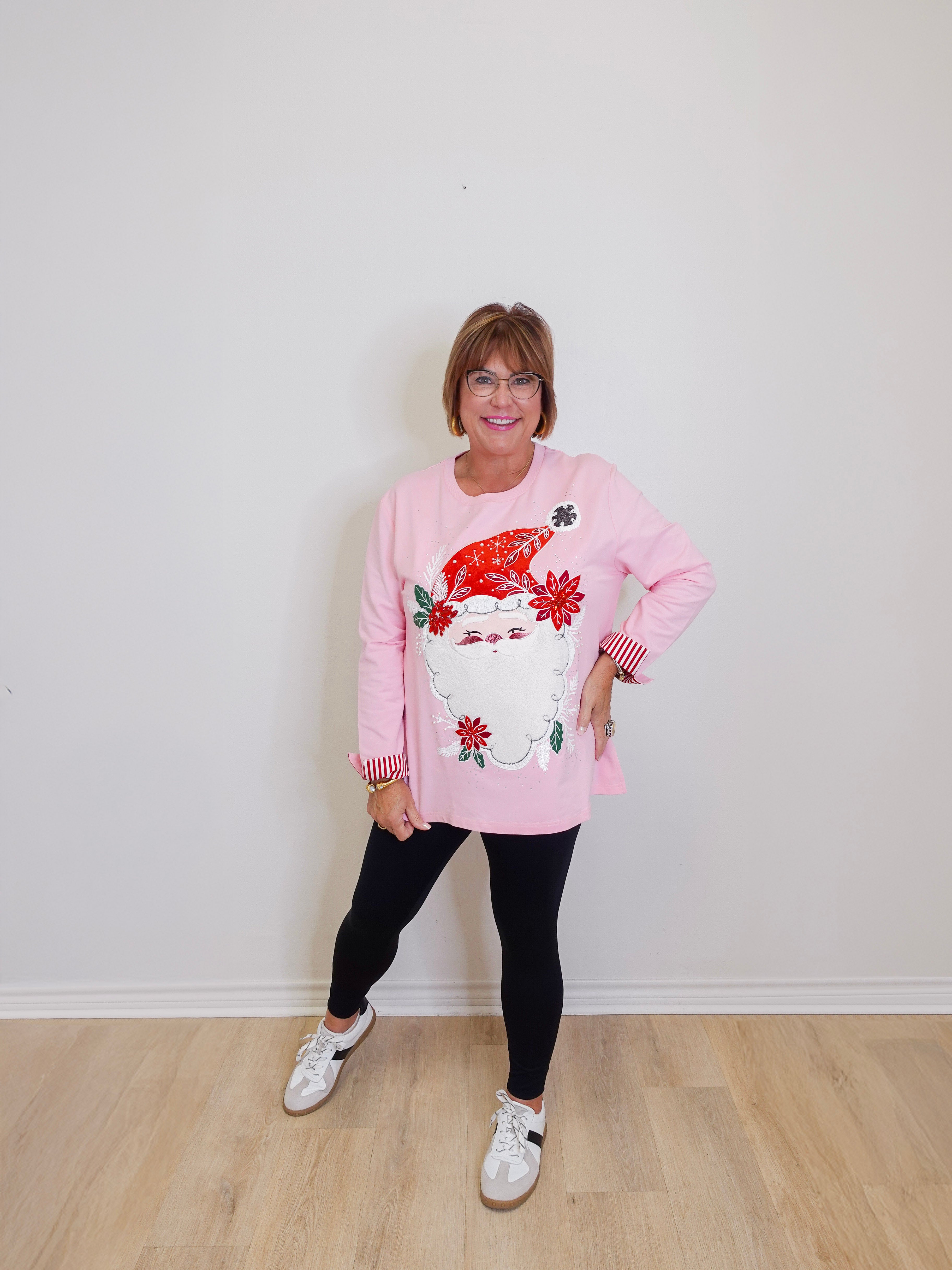 woman wearing a pink long sleeve Santa baby sweatshirt against a white background. 