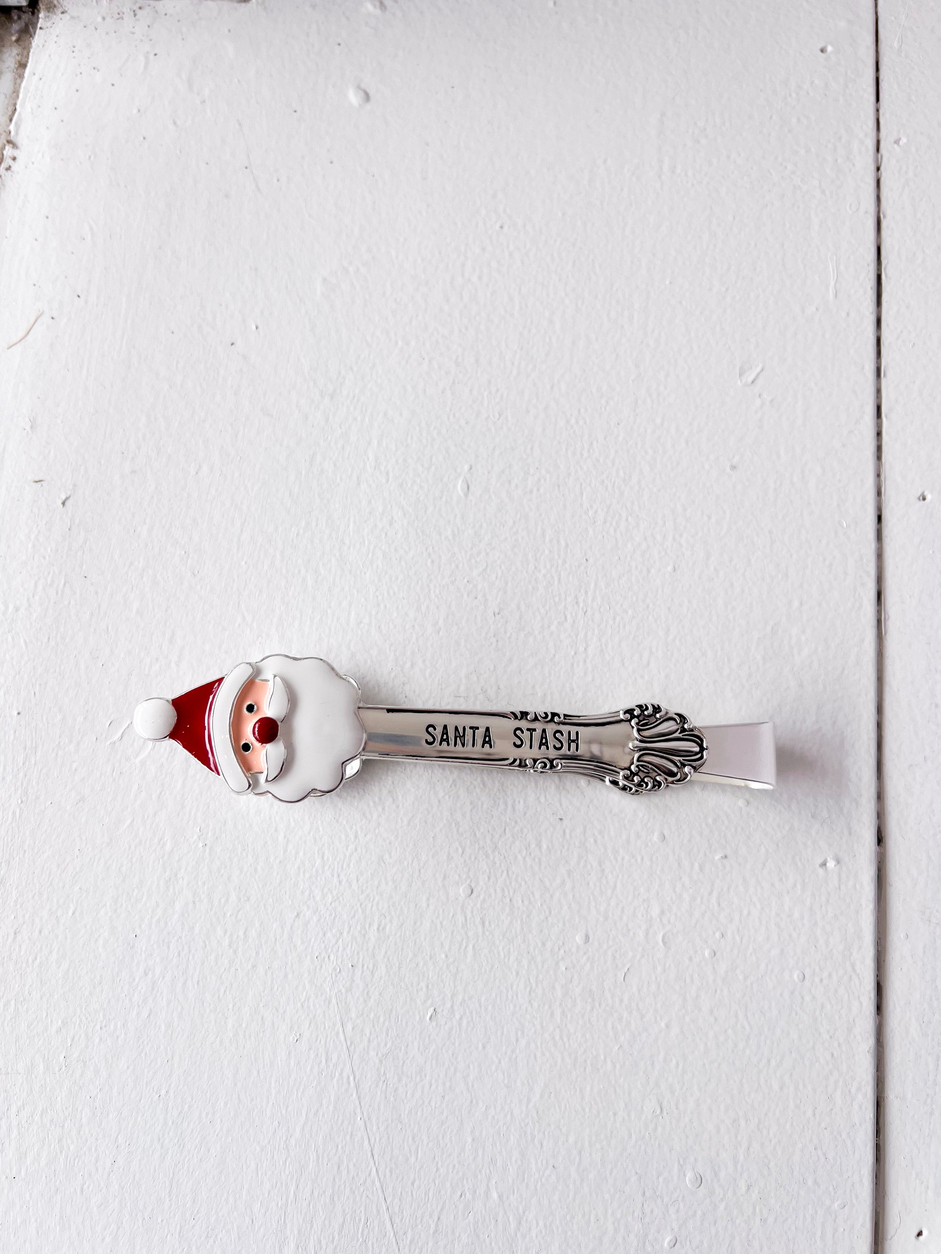 Spoon with Santa Claus design and 'Santa Stash' text on a white wooden surface