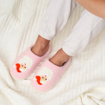Pink slippers with cartoon face design worn by a person on a white textured surface