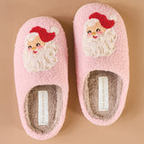 Pair of pink slippers with Santa face design on a beige background